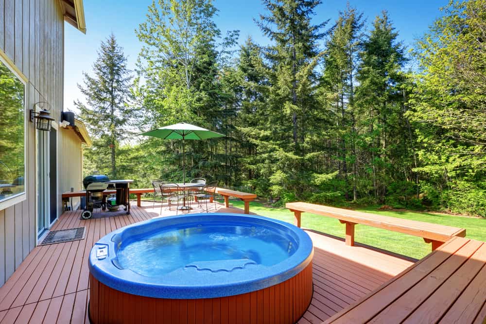 A traditional garden tub setting with a view of nature An elegant garden tub placed in a sunroom with a view of a lush green garden