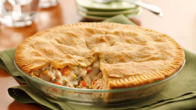 A slice of Classic Chicken Pot Pie A freshly baked homemade chicken pot pie in a glass baking dish