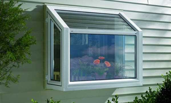 A classic kitchen garden window projecting outward A beautiful kitchen garden window filled with small potted plants and herbs