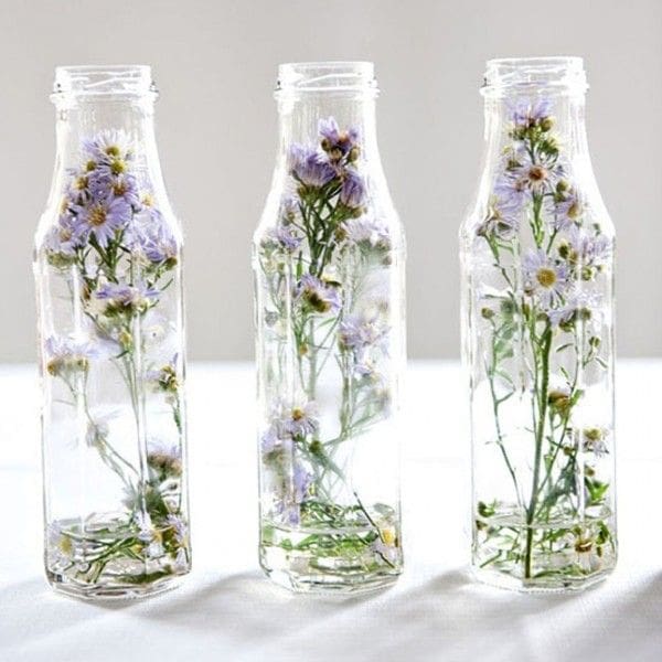 Single dried flowers in vintage glass bottles Single stems of dried flowers placed elegantly in small transparent vintage glass bottles
