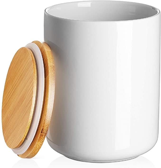 A white ceramic kitchen compost bin A stylish white ceramic indoor compost bin sitting on a kitchen counter