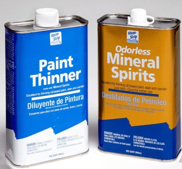 Mineral Spirits A bottle of mineral spirits sitting next to a paint brush.