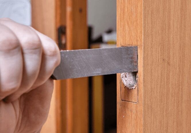 Preparing the Door for the New Doorknob Inspecting the empty hole in the door after removing the old hardware.