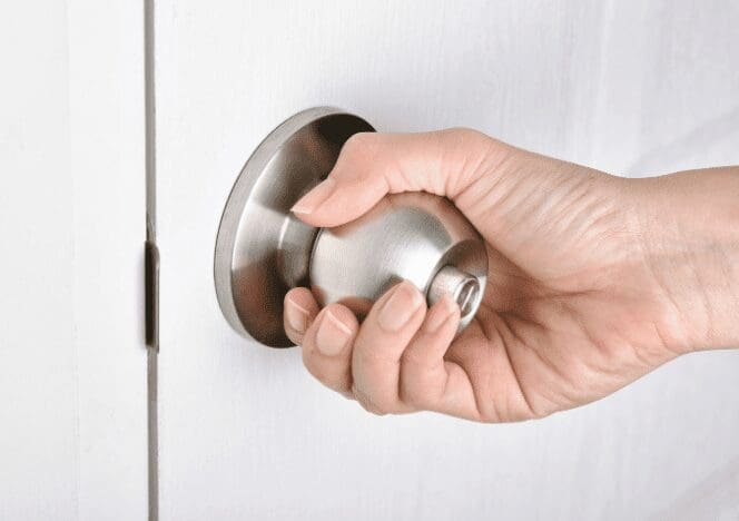 Testing the New Door Knob Turning the newly installed doorknob to test the latch and locking mechanism.
