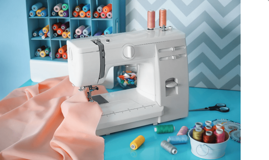 Beginner Sewing Machine Beginner-friendly sewing machine with fabric thread scissors and sewing accessories on a table