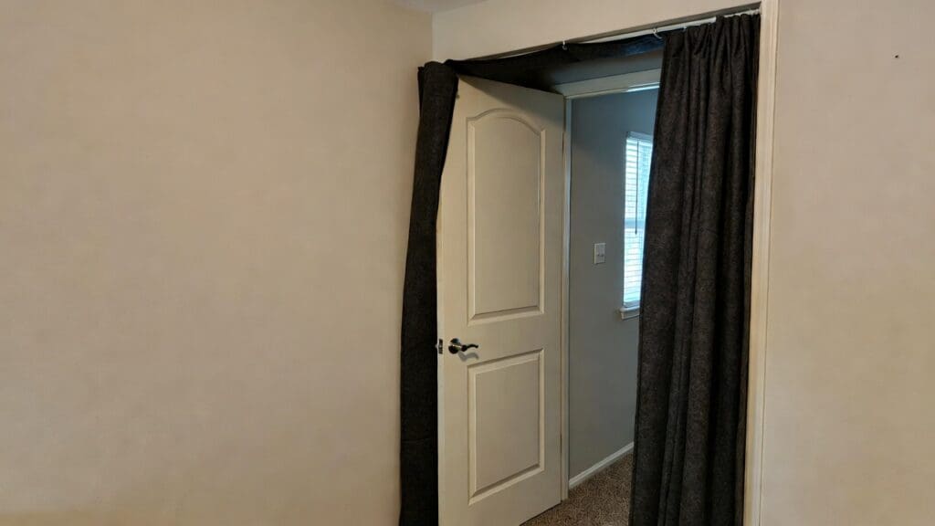 A homeowner installing an automatic drop door sweep to block noise from entering a bedroom. A homeowner installing an automatic drop door sweep to block noise from entering a bedroom.