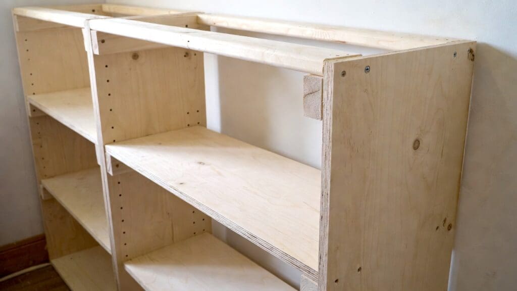 Beginner DIY bookshelf project with plywood shelves, clamps, drill, sander, and wood boards in a workshop Beginner DIY bookshelf project with plywood shelves, clamps, drill, sander, and wood boards in a workshop