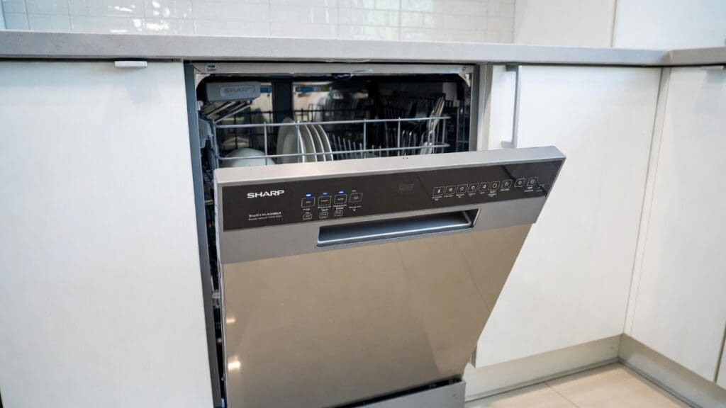 Stainless steel Sharp dishwasher installed in a modern kitchen with clean dishes and silverware racks Stainless steel Sharp dishwasher installed in a modern kitchen with clean dishes and silverware racks